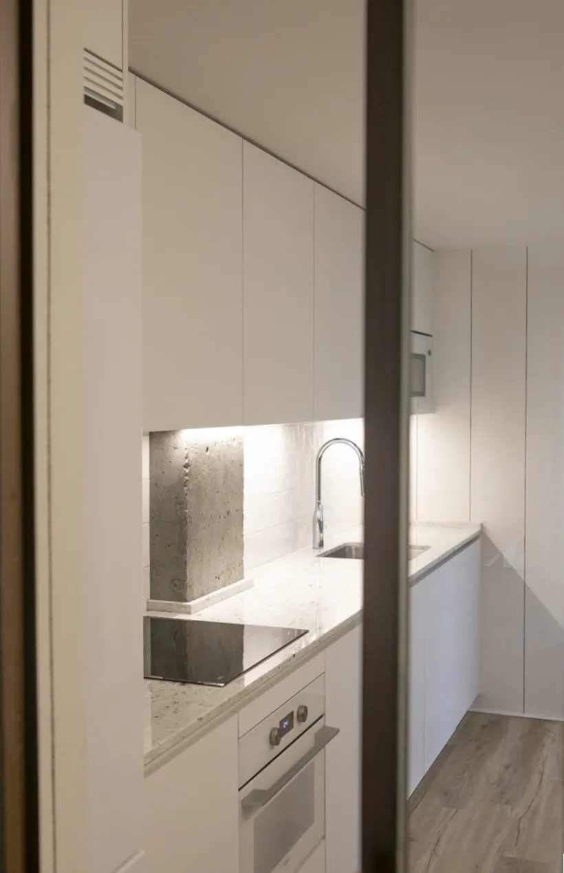 Cocina reformada con distribución funcional, mobiliario integrado y materiales de acabado continuo